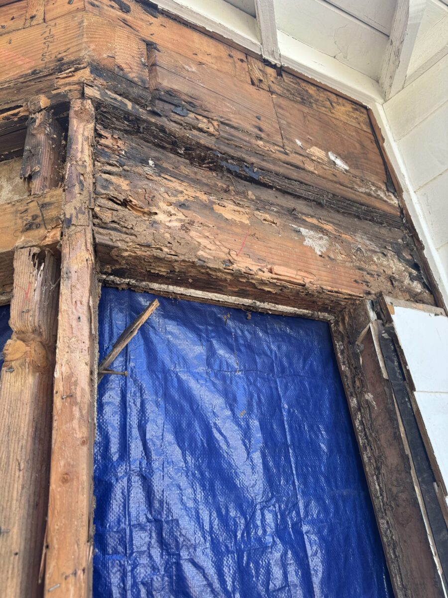 Close-up of damaged wooden frame with a blue tarp behind it.