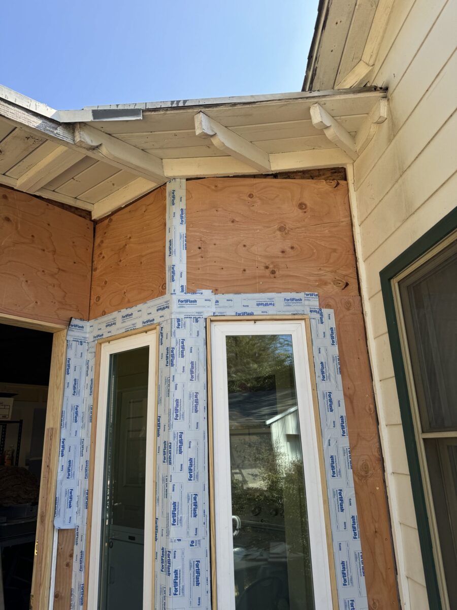 Partially constructed exterior corner with new windows and waterproofing.