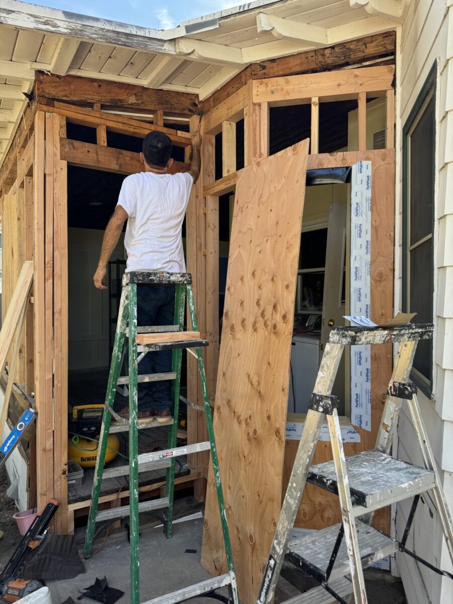 Two men working on wooden construction, one on a ladder.