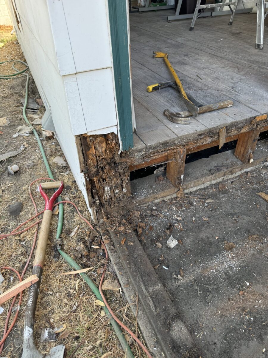 Damaged wooden porch with tools and debris around.