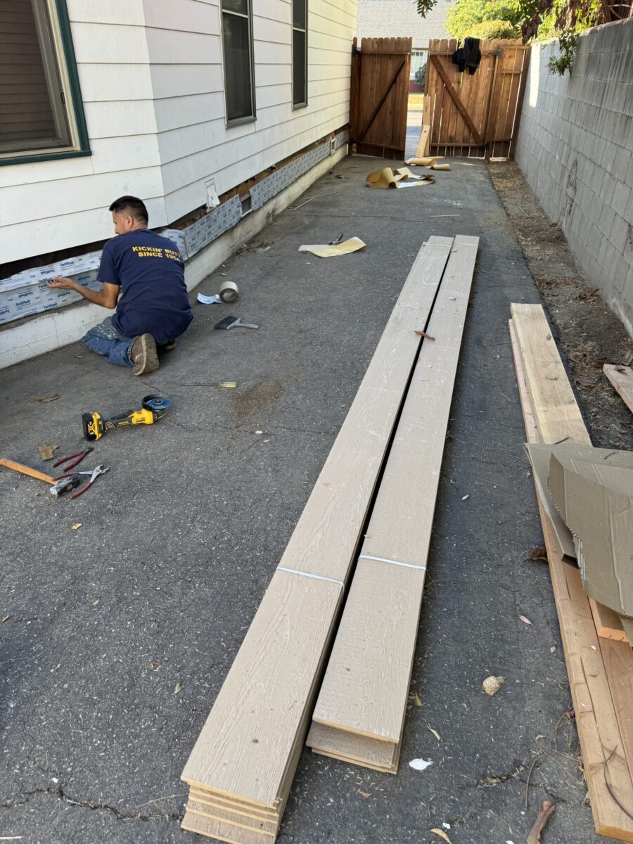 Person assembling wooden planks outside near a building.