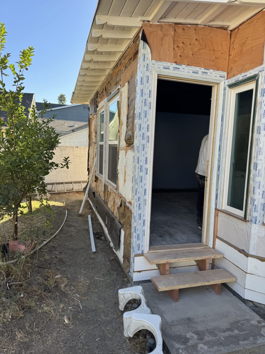 Partially constructed house with open doors and a small wooden step outside.
