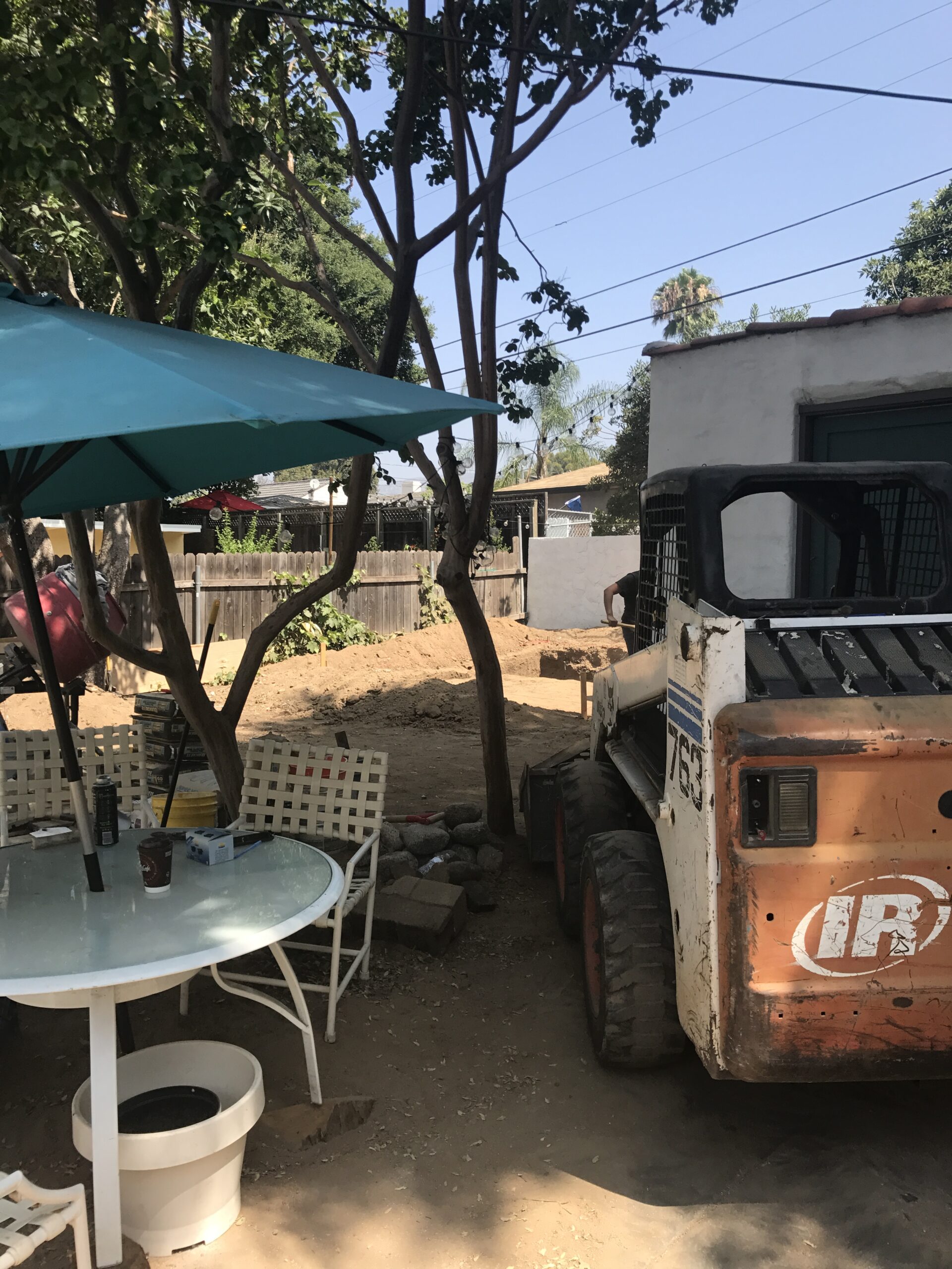 Backyard with construction vehicle and patio furniture.