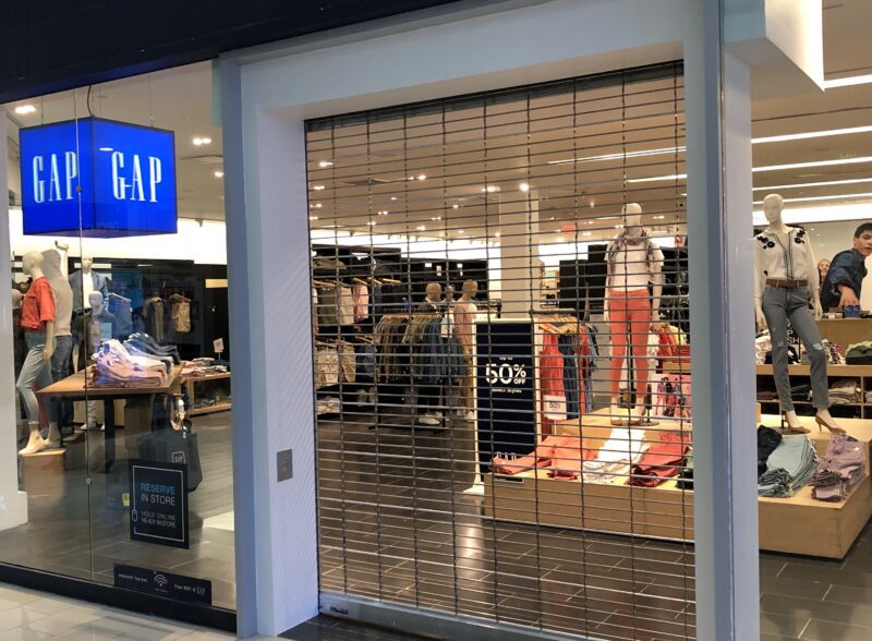Store with closed gate and visible clothing display.