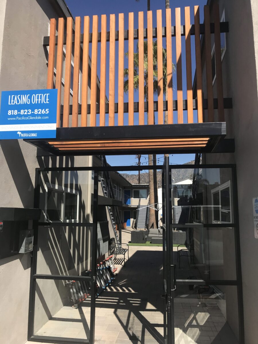 A narrow outdoor stairway with a blue sign reading 'Leasing Office'. A narrow outdoor stairway with a blue sign reading 'Leasing Office'.