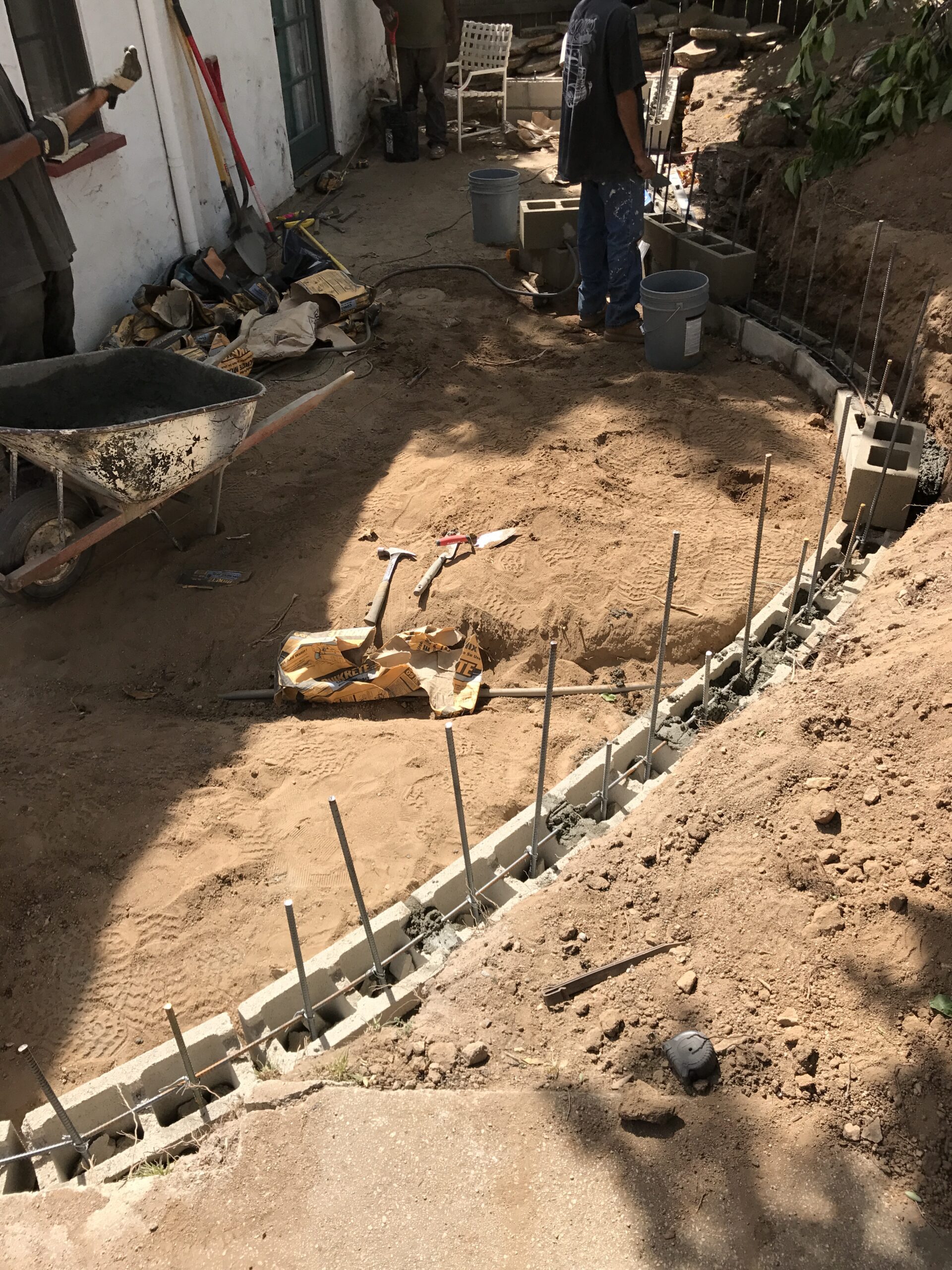 Backyard construction with sand and tools.