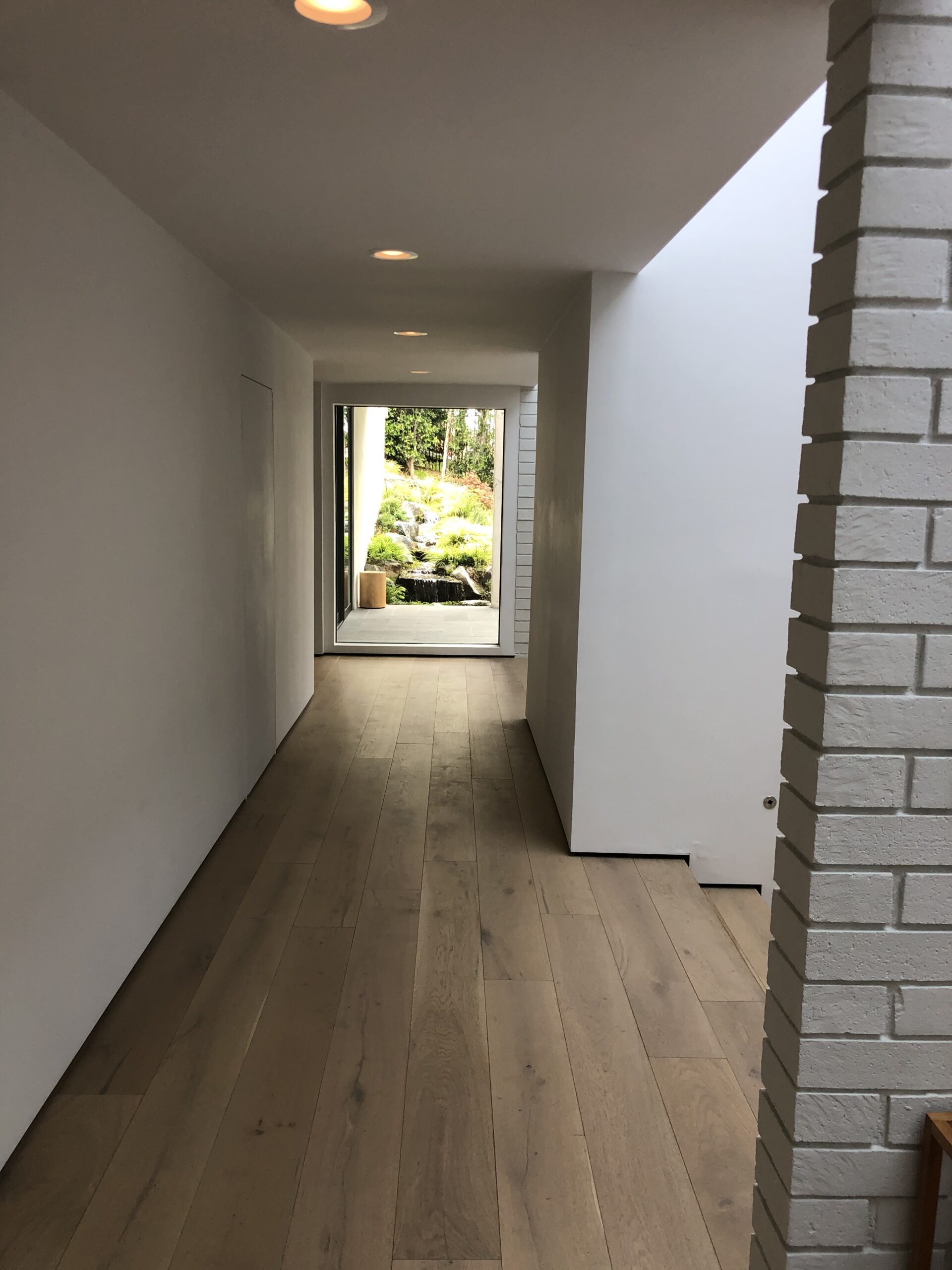 Minimalist hallway with wooden floor and garden view.