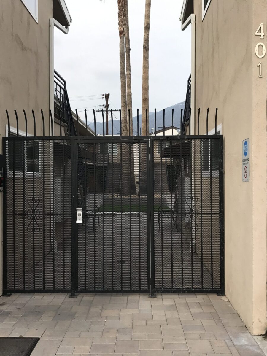 A narrow alley with a closed black metal gate between two buildings. A narrow alley with a closed black metal gate between two buildings.