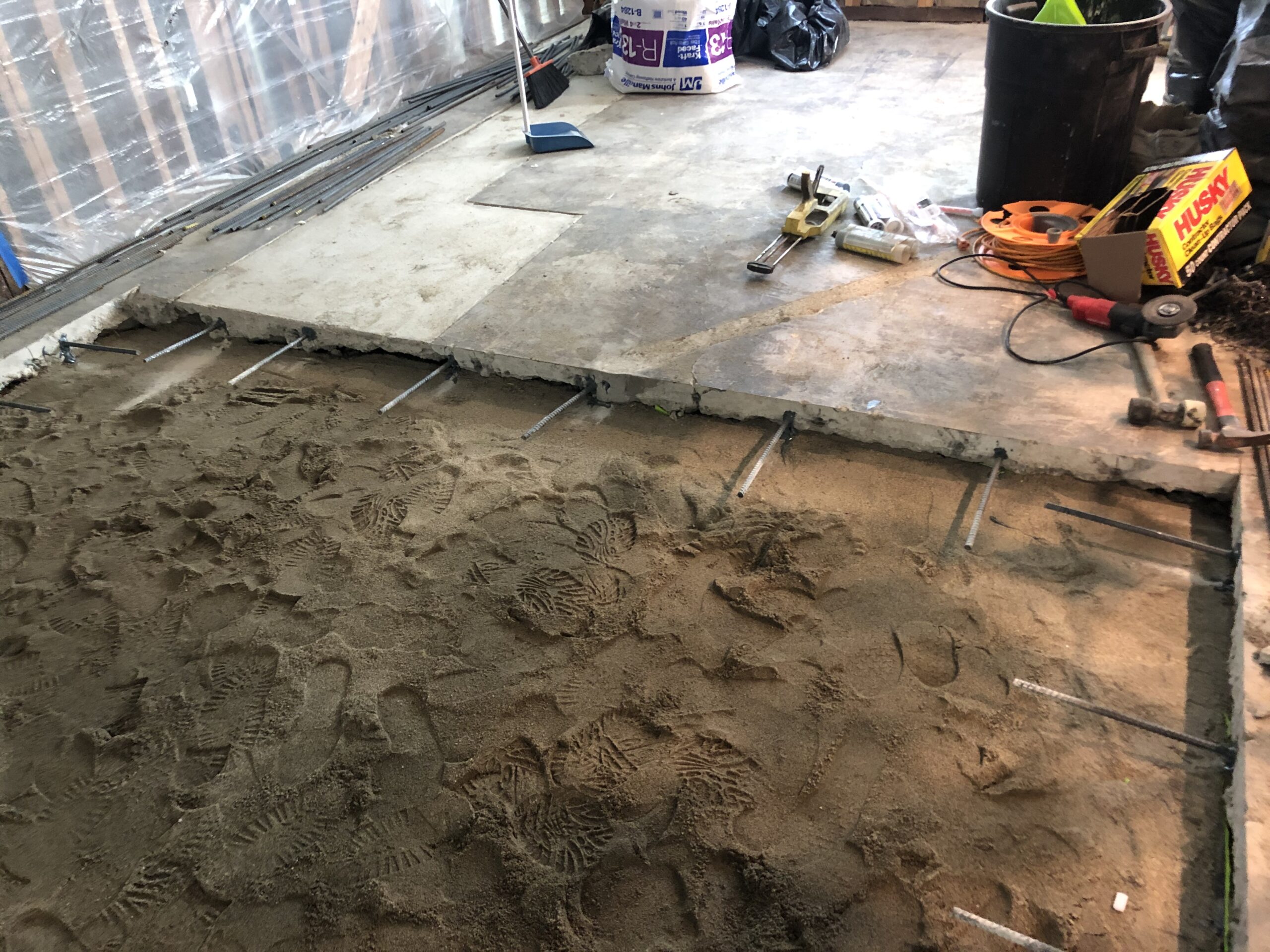 Construction site with freshly poured concrete and sandy ground.