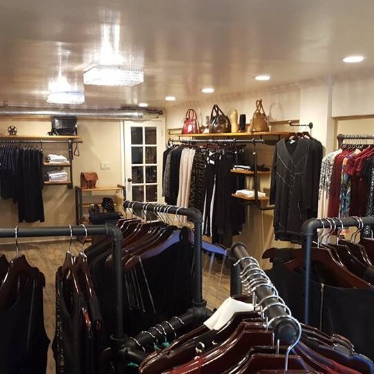 Clothing racks filled with jackets and coats inside a warmly lit store. Clothing racks filled with jackets and coats inside a warmly lit store.