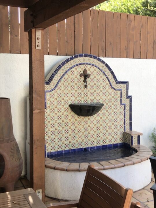 Decorative tiled wall fountain with a religious cross above it. Decorative tiled wall fountain with a religious cross above it.