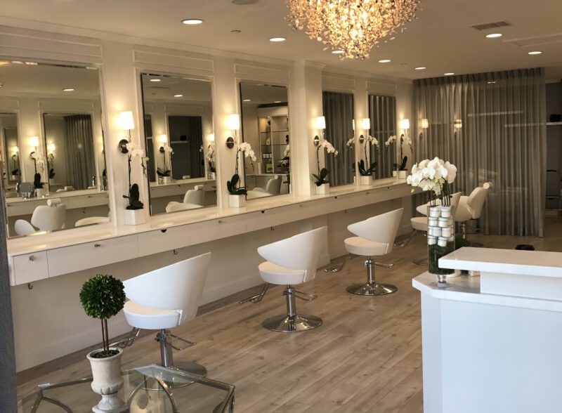 Elegant modern salon with white chairs and a chandelier.