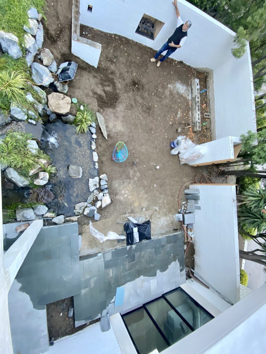 A backyard garden with a small pond and garden tools scattered around. A backyard garden with a small pond and garden tools scattered around.