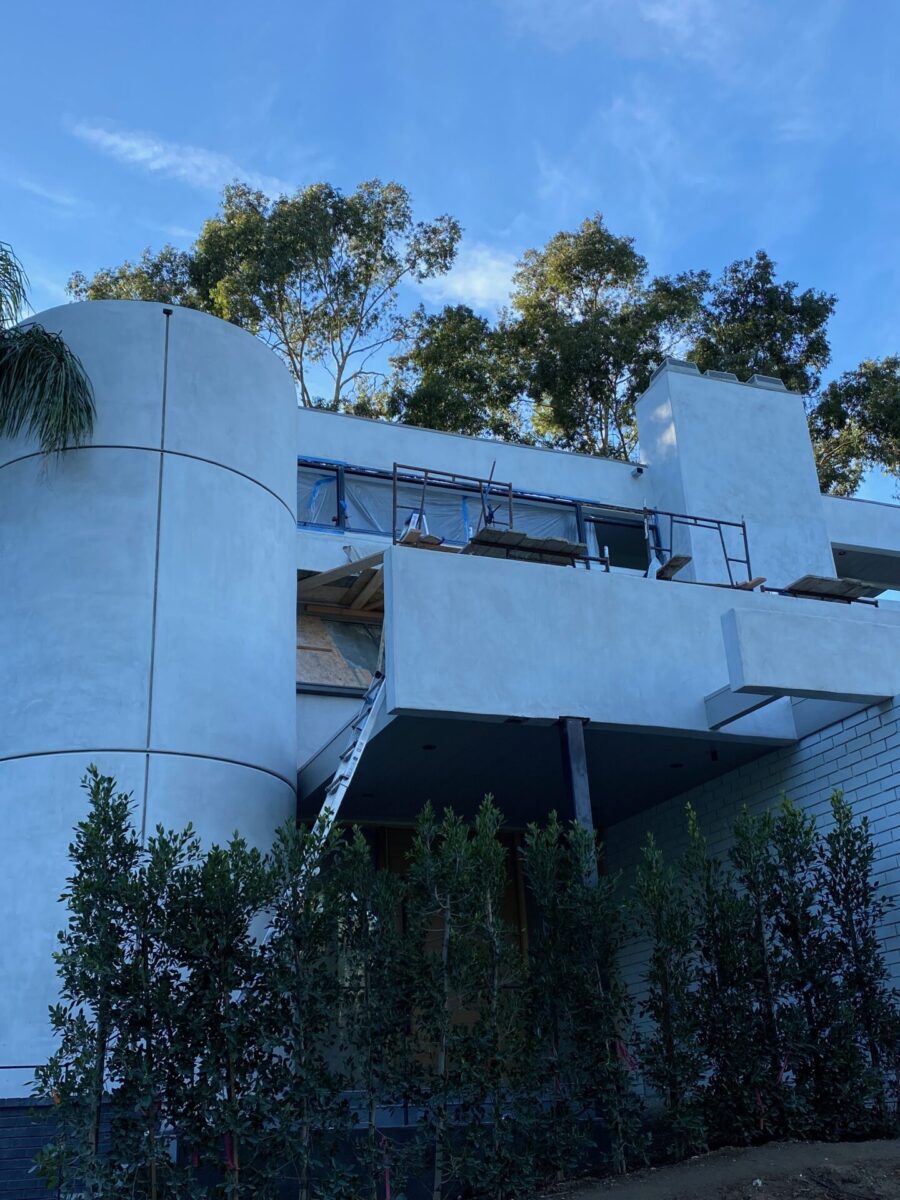 Modern white building surrounded by trees under a blue sky. Modern white building surrounded by trees under a blue sky.