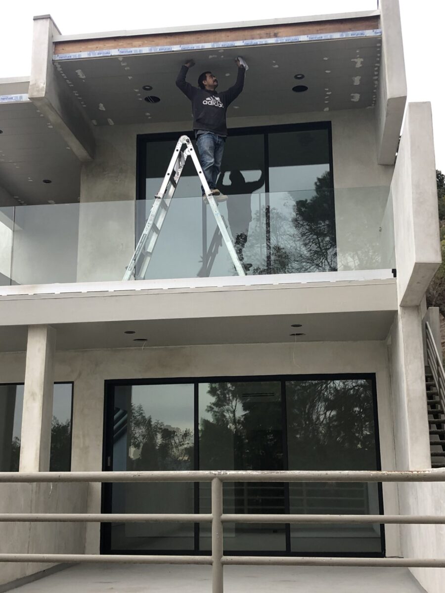 Person on ladder cleaning glass balcony on modern building. Person on ladder cleaning glass balcony on modern building.