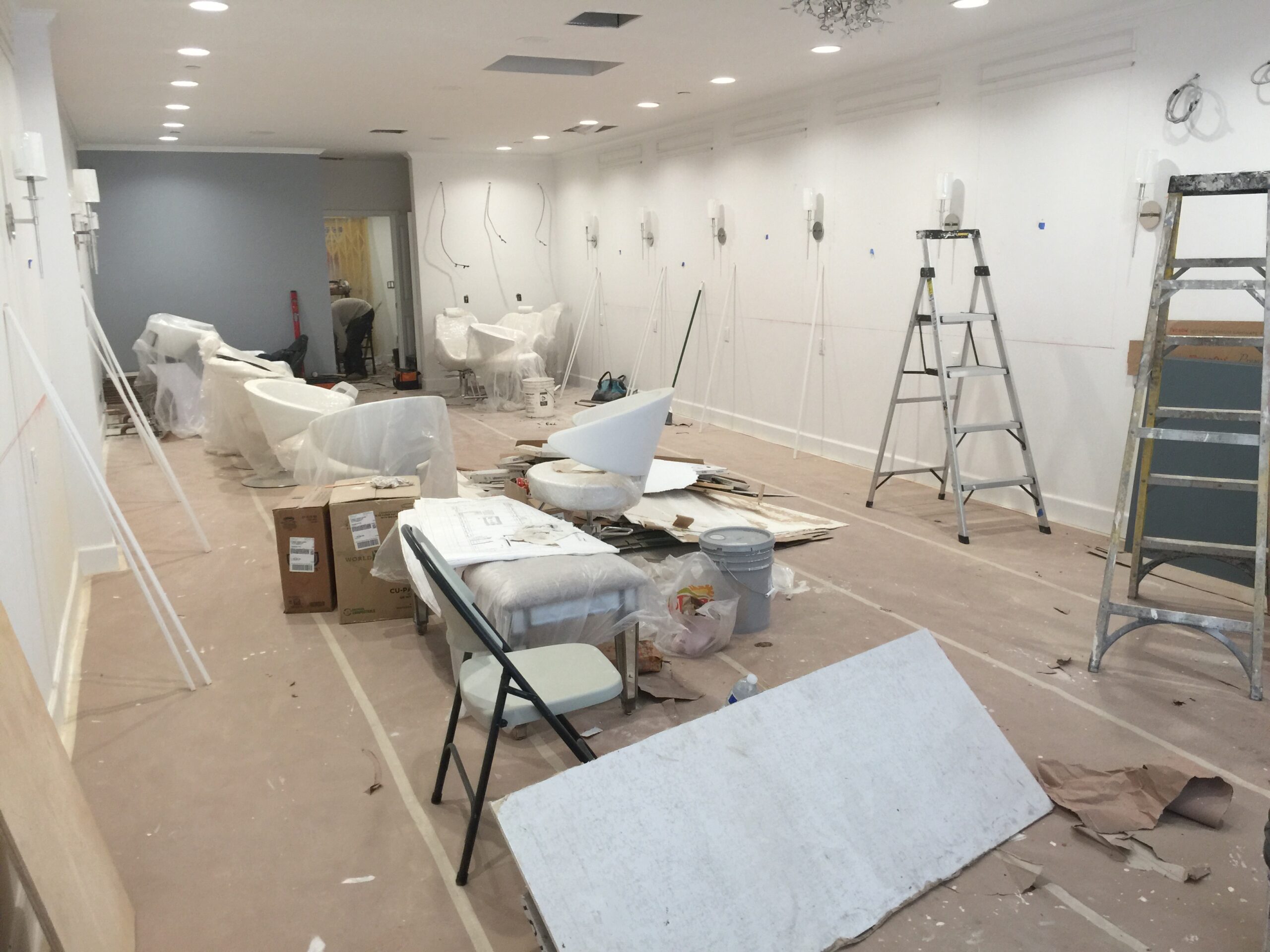 Room under renovation with covered furniture and tools scattered around.