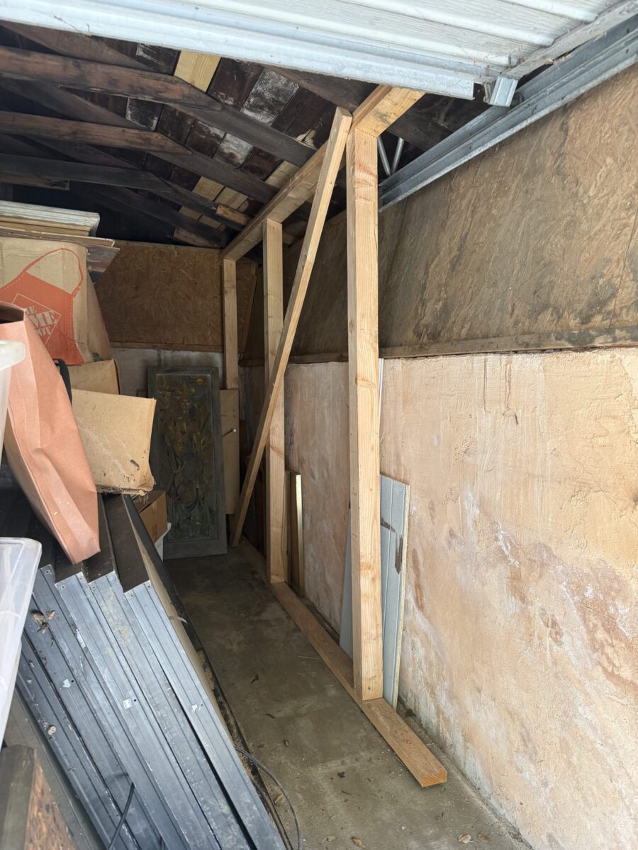 Cluttered storage area with wooden shelves and various materials.