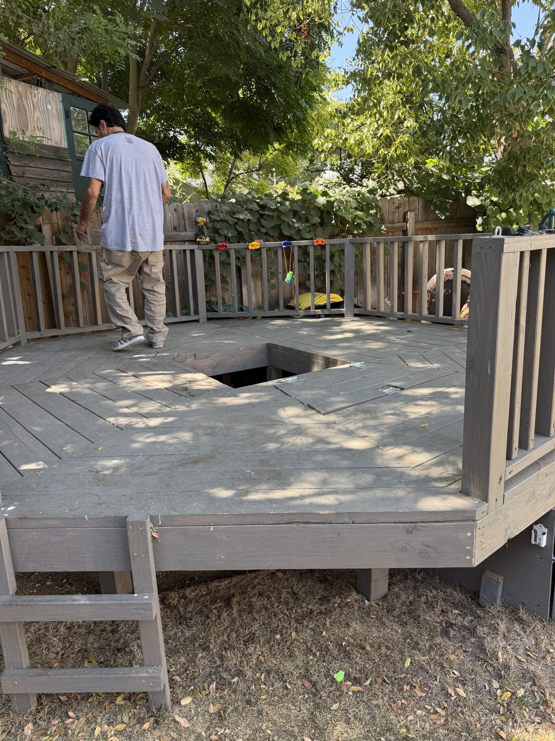 A wooden deck under construction with a square hole in the center.