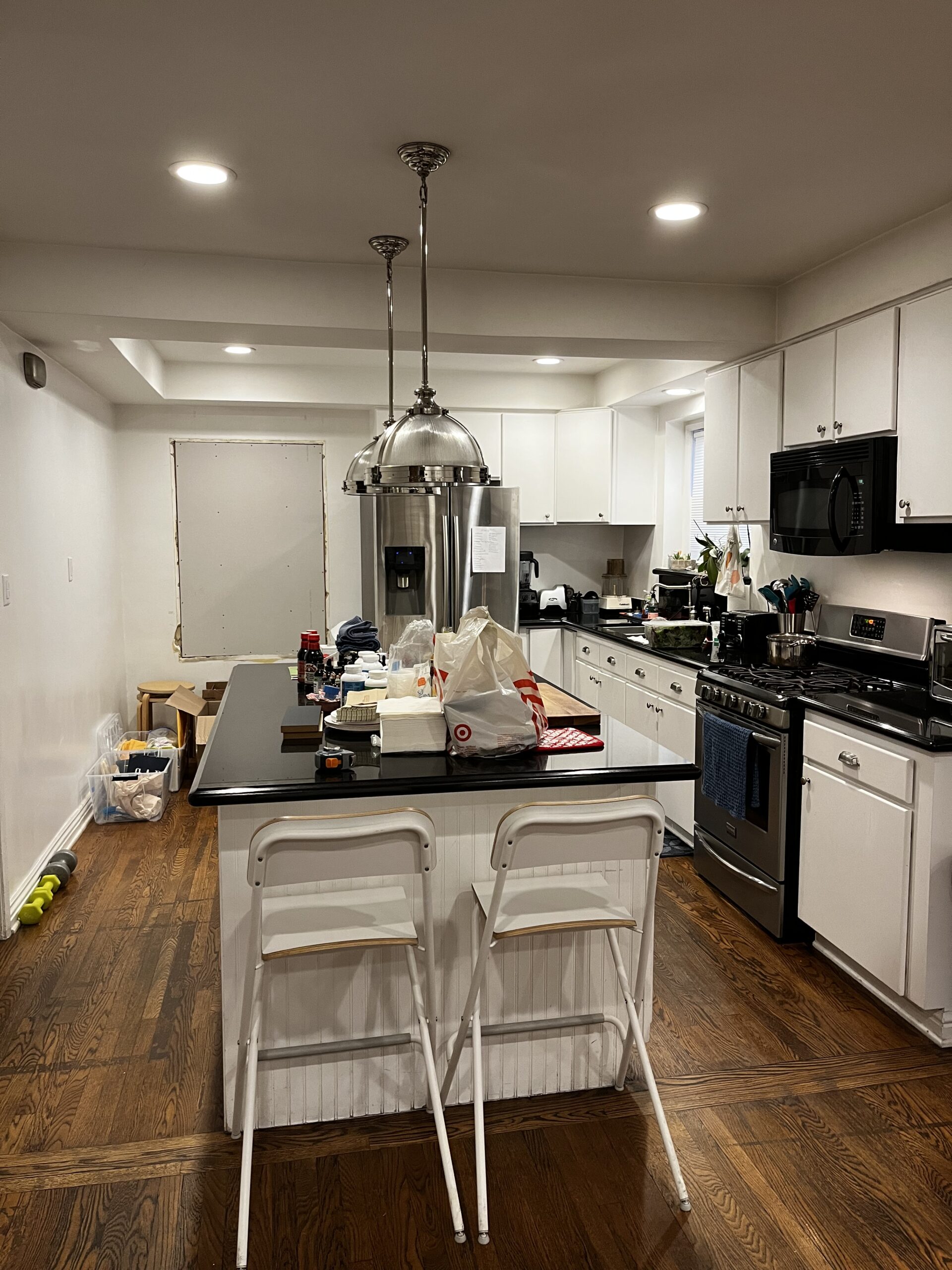 Modern kitchen with island and hanging lights.