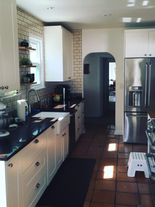 Modern kitchen with white cabinets, black countertops, and stainless steel appliances. Modern kitchen with white cabinets, black countertops, and stainless steel appliances.