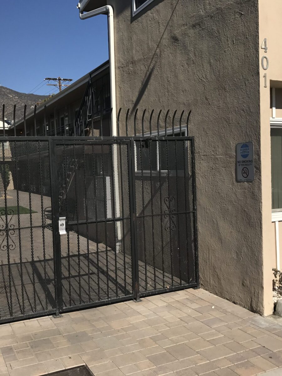 Gated entrance to a residential area with stairs and a palm tree. Gated entrance to a residential area with stairs and a palm tree.