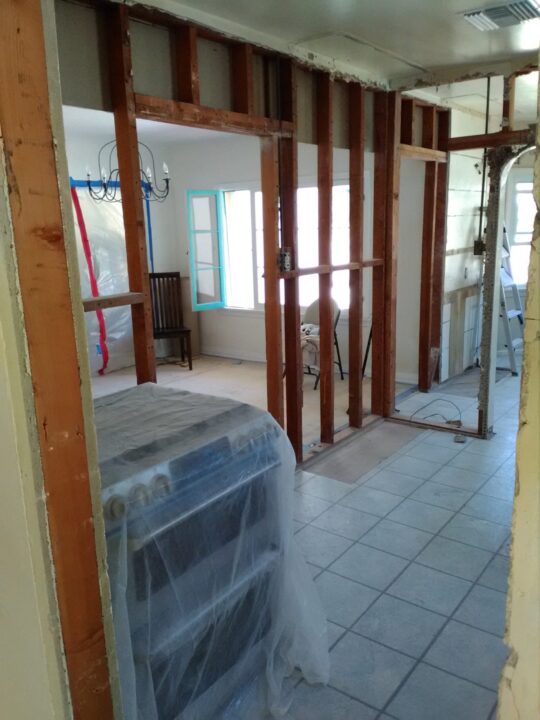 Interior of a house under renovation with exposed wooden framing and covered furniture. Interior of a house under renovation with exposed wooden framing and covered furniture.