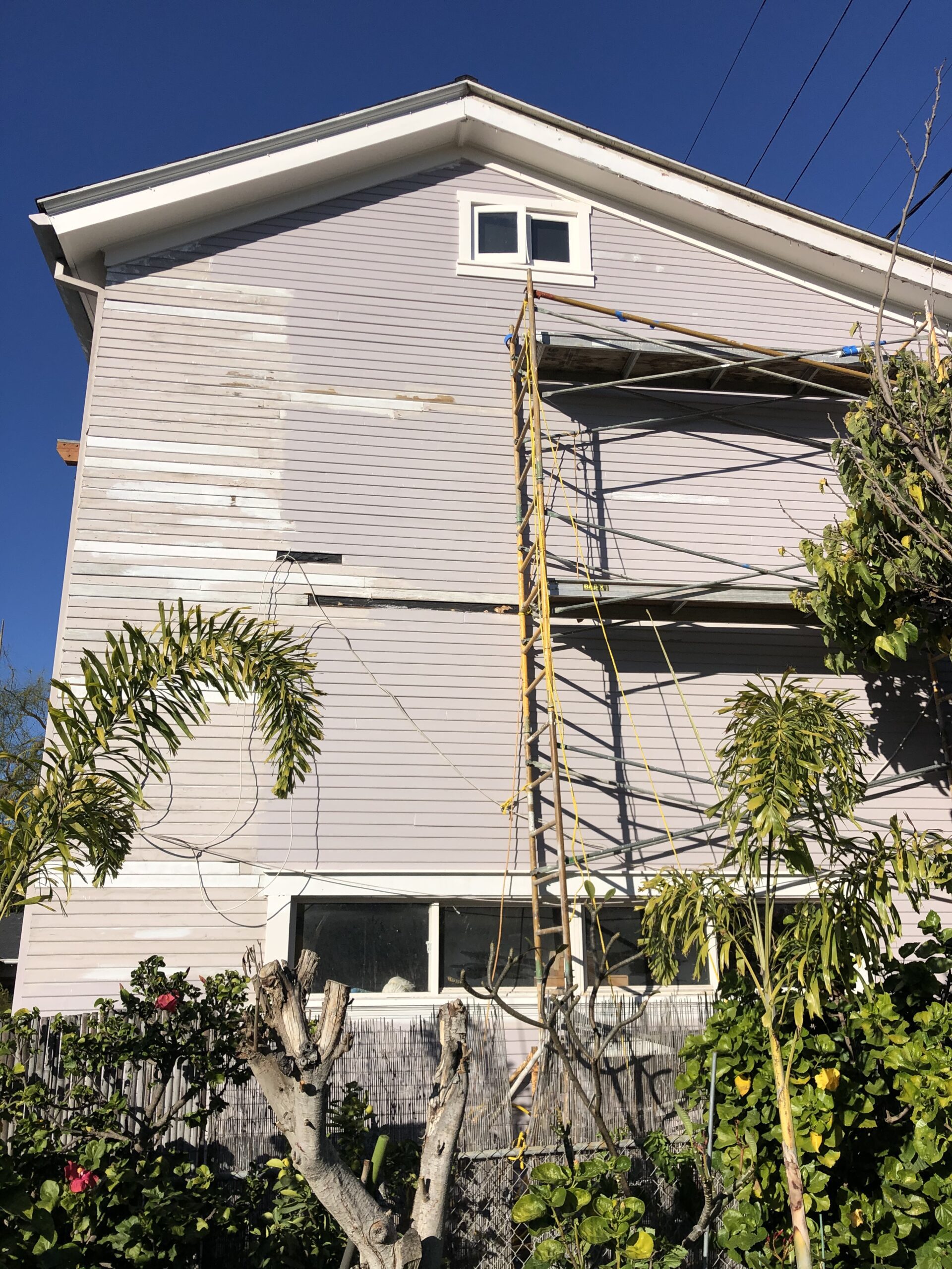 Scaffolding set up for house siding painting or repair on a sunny day.