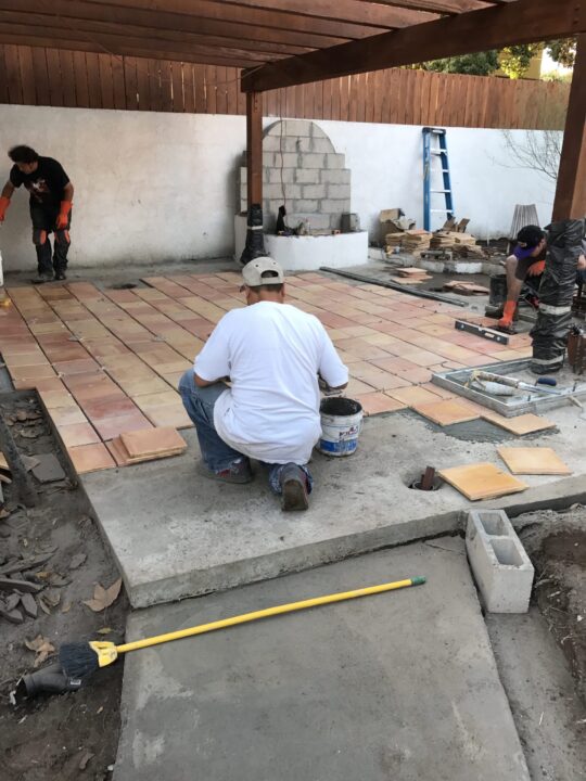 Workers laying tiles on a floor in an indoor construction site. Workers laying tiles on a floor in an indoor construction site.