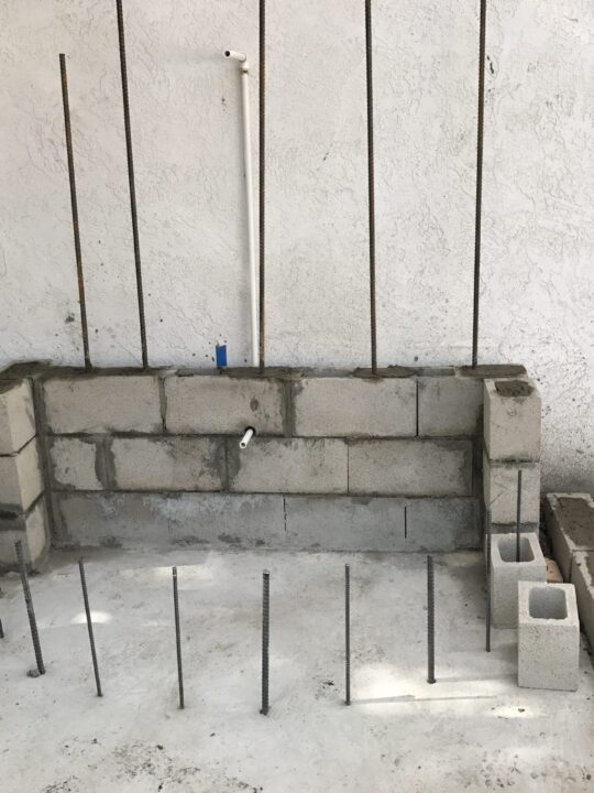 Partially built brick wall with vertical metal rods for reinforcement. Partially built brick wall with vertical metal rods for reinforcement.